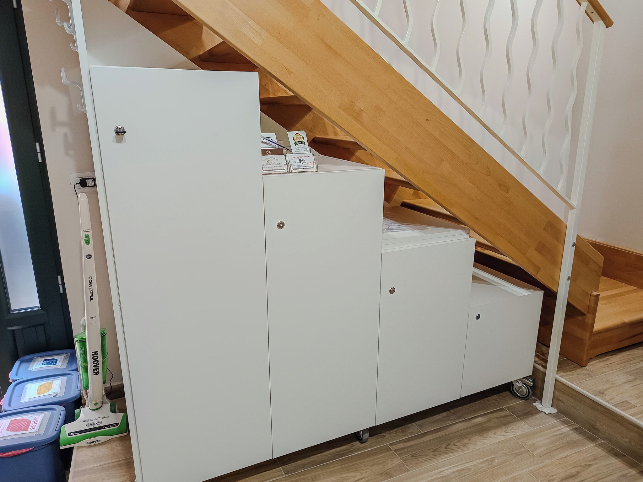 Un meuble de rangement blanc doté d’un appareil de marche intégré et d’un petit escalier en bois menant à un niveau supérieur.