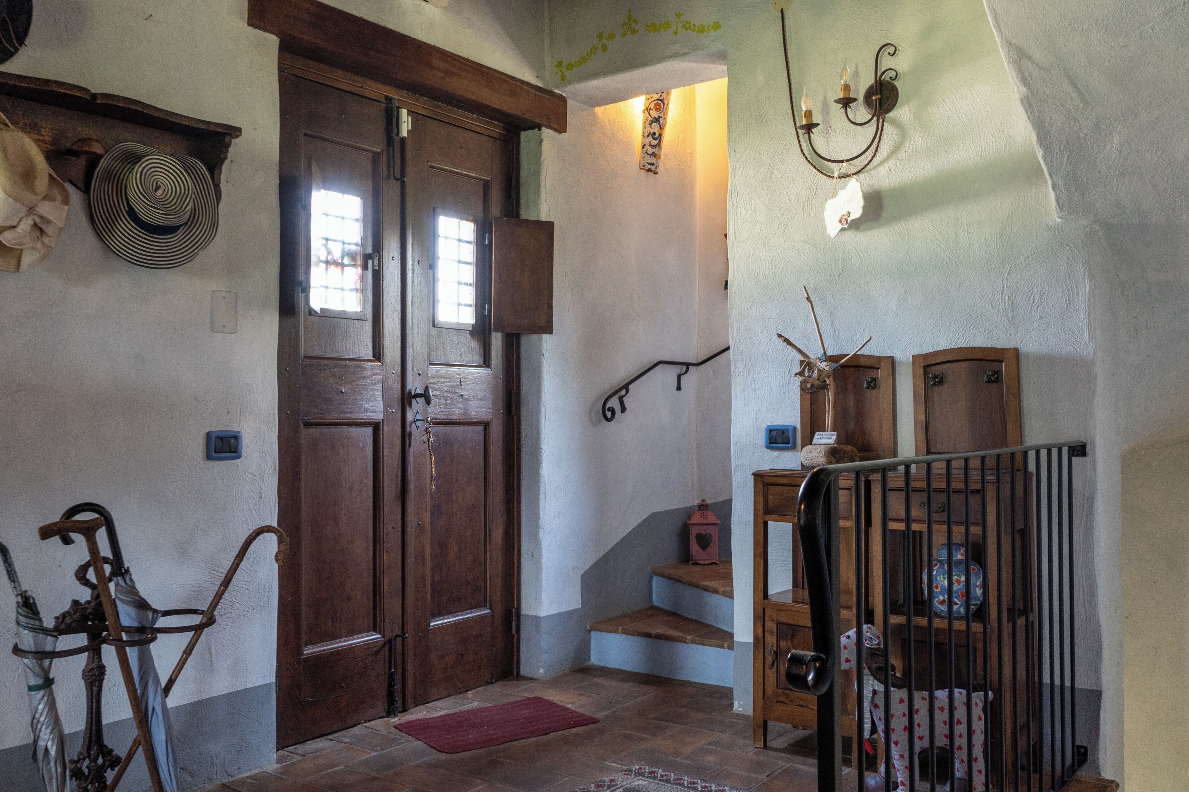 A wooden staircase with a handrail, a door with a window, and a wall-mounted light fixture.
