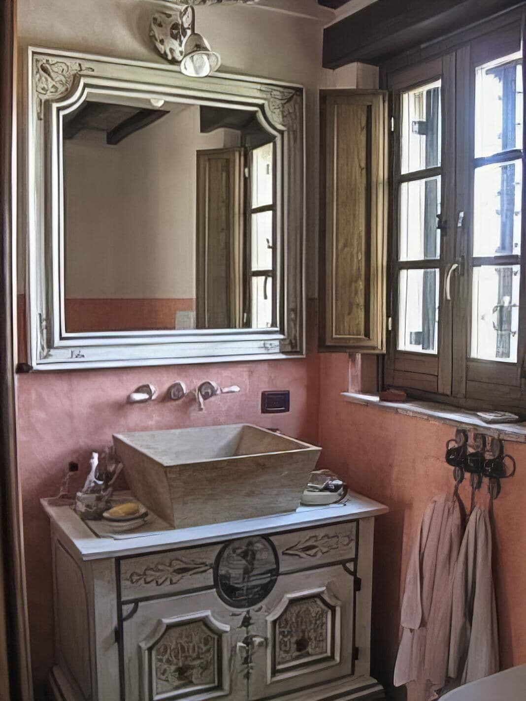 A bathroom with a wooden vanity, a large mirror, and a window with wooden shutters.