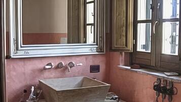 A bathroom with a wooden vanity, a large mirror, and a window with wooden shutters.