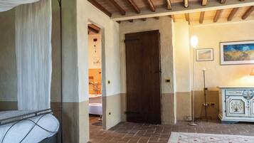 Un dormitorio con cama, una puerta de madera, una lámpara de pie y un cuadro en la pared.