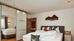Una camera da letto moderna con un letto grande, uno specchio, una panca in legno e un comodino.
