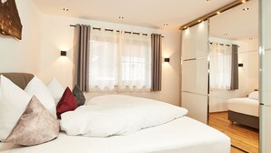 Ein modernes Schlafzimmer mit einem großen Bett, einem Spiegel und einer Schiebetür zu einem Badezimmer.