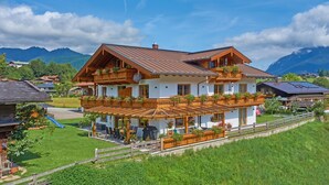 Ein zweistöckiges Holzhaus mit Balkon, Terrasse und einer Rutsche im Garten.