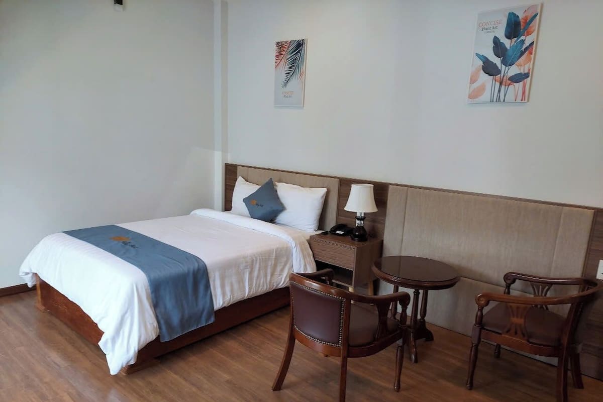 Een hotelkamer met een bed, twee stoelen, een tafeltje en een nachtkastje.