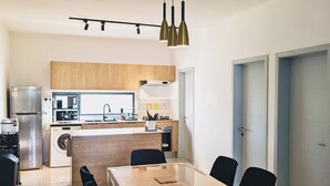 A modern kitchen with a central island, black chairs, and a dining table.