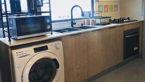 A modern kitchen with a built-in washer and dryer, a microwave, a coffee maker, and a gas stove.
