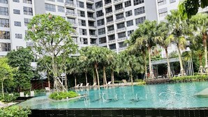 A swimming pool surrounded by palm trees and a building with balconies. - AGILE Residences by Luna (Kuala Lumpur)