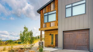 A modern two-story house with a wooden facade, large windows, and a garage.