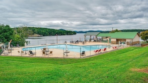 A swimming pool with lounge chairs and tables, surrounded by a fence, with a building in the background. - Home w/ Decks & River Access in Mt Gilead! (Mt Gilead)