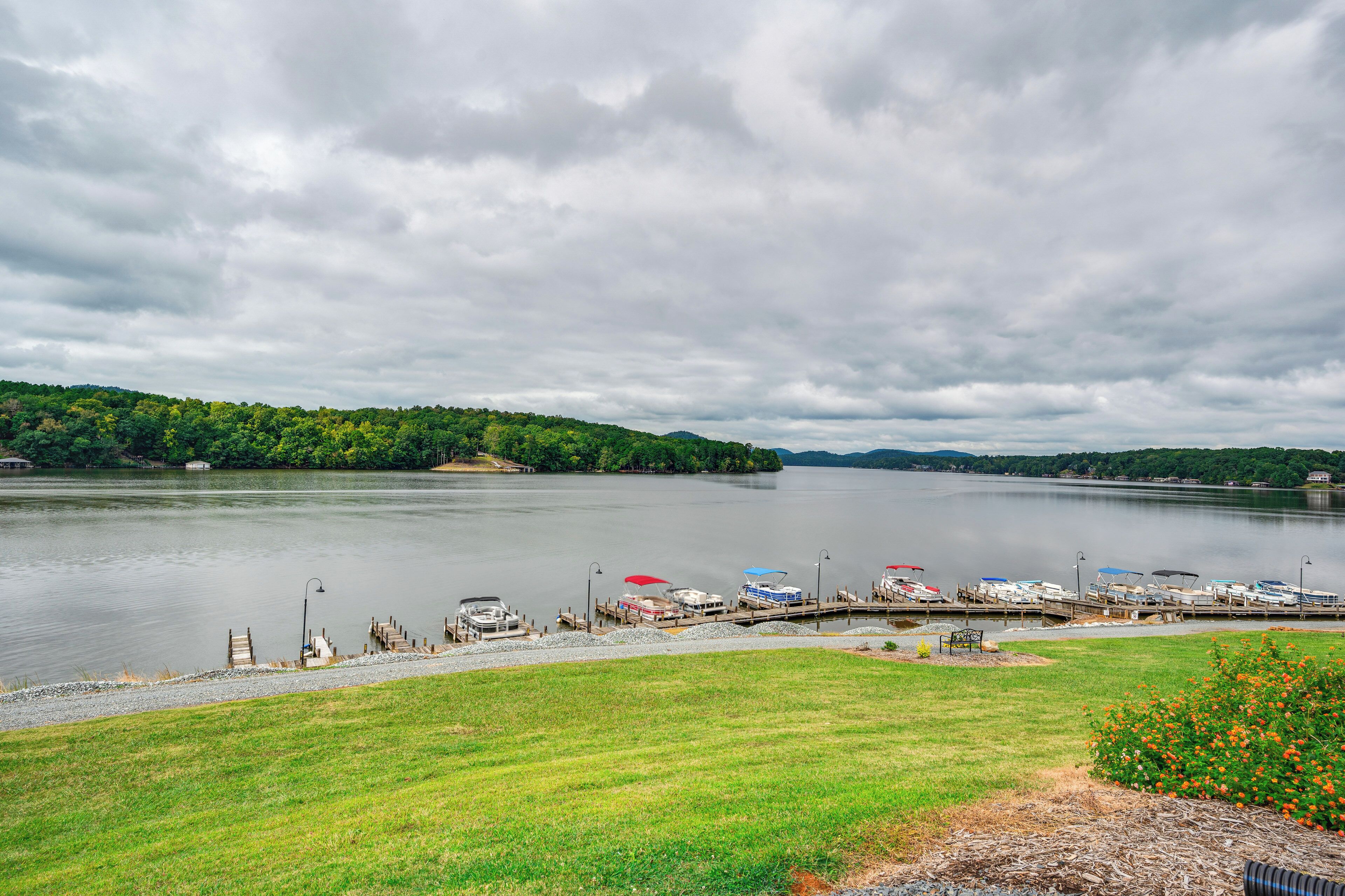 A lakeside dock with boats and a grassy area in the foreground.