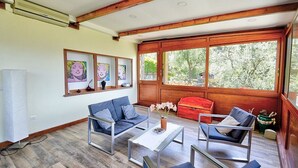 A living room with modern furniture, large windows, and artwork on the wall.