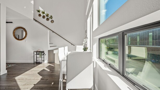 Ein modernes Interieur mit Treppe, weißen Möbeln und einem großen Fenster.