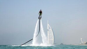 Iemand gaat jetskiën op het water, met een groot gebouw op de achtergrond.