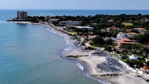 Uma vila costeira com praia, edifícios residenciais e um grande hotel.