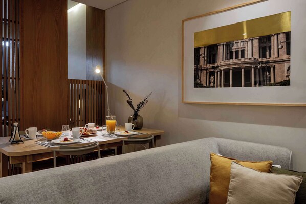 A modern dining area with a wooden partition, a table set with breakfast, and a framed picture on the wall.