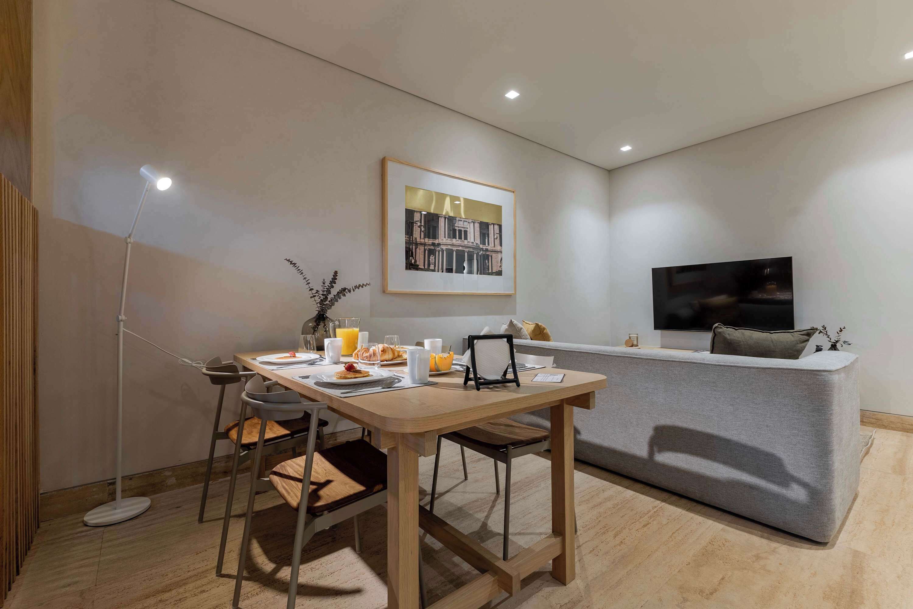 Ein modernes Wohnzimmer mit Essbereich, einer Couch, einem Fernseher und einem gerahmten Bild an der Wand.