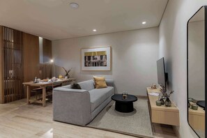 A modern living room with a sofa, coffee table, TV, and a dining area with a table and chairs.