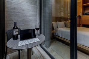 Una camera moderna con un letto, un tavolino con un portatile e vino, e una bottiglia di vino.