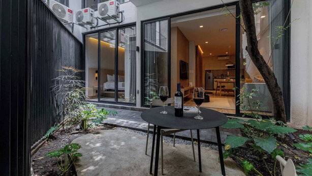 A modern outdoor patio with a table set for two, a bottle of wine, and a glass. - Capitalia | Private Patio – Peaceful Polanco Stay (Ciudad de México)