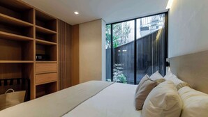 A bedroom with a bed, a wooden wardrobe, and a sliding glass door leading to an outdoor area. - Capitalia | Private Patio – Peaceful Polanco Stay (Ciudad de México)