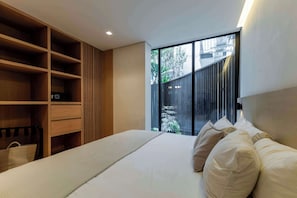 A bedroom with a bed, a wooden wardrobe, and a sliding glass door leading to an outdoor area.