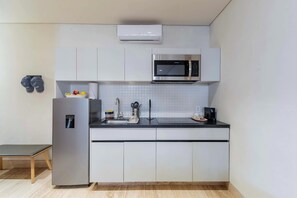Une cuisine moderne équipée d’un four à micro-ondes encastré, d’un réfrigérateur et d’un évier.
