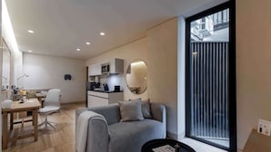 Een moderne woonkamer met een bank, een eettafel en een keuken op de achtergrond.