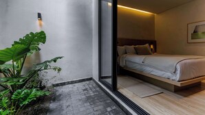 Een moderne slaapkamer met een bed, nachtkastje, wandlamp en groot raam.