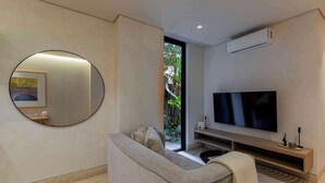 Een moderne woonkamer met een bank, een televisie, een ronde spiegel en een airconditioning.