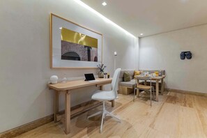 A modern room with a desk, chair, and a dining area with a sofa and table.