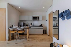 Une cuisine compacte équipée d’un four à micro-ondes, d’une table à manger avec des chaises et d’un miroir sur lequel sont accrochés des chapeaux.
