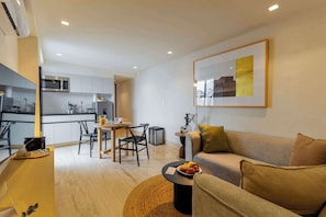 A modern living room with a sofa, a dining table, and a kitchen area in the background.