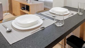 Ein ordentlich gedeckter Esstisch mit Tellern, Besteck und Gläsern auf einer strukturierten Tischmatte.