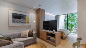 Ein modernes Wohnzimmer mit einer Couch, einem Fernseher, einer Holz-Unterhaltungseinrichtung, einem Bett und einem Essbereich.