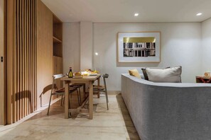 Un salon moderne comprenant un coin repas, un canapé gris, une cloison en bois et un tableau encadré au mur.
