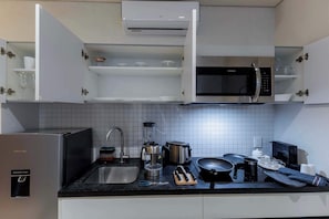 A kitchen with a refrigerator, microwave, toaster, sink, and various utensils.