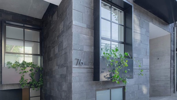 A building with dark stone exterior walls, large windows, and a number '76' on one wall. - Park Condesa | 2BR, Rooftop Spa & Gym (Ciudad de México)