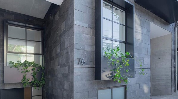 A building with dark stone exterior walls, large windows, and a number '76' on one wall. - Capitalia | Two King Suites in Heart of Condesa (Ciudad de México)