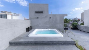A rooftop with a rectangular hot tub, a concrete wall, and a clear sky. - Park Condesa | 2BR, Rooftop Spa & Gym (Ciudad de México)