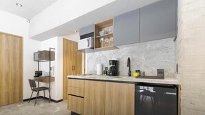 Une cuisine compacte avec des meubles en bois, un lave-vaisselle encastré et un plan de travail sur lequel se trouvent une machine à café et d’autres appareils.