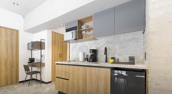 Une cuisine compacte avec des meubles en bois, un lave-vaisselle encastré et un plan de travail sur lequel se trouvent une machine à café et d’autres appareils.