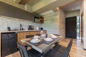 A modern kitchen with a built-in dishwasher, a dining area with a marble countertop, and a large window providing natural light.
