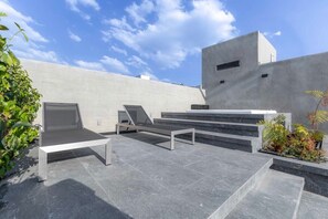 Eine moderne Außenpatio mit minimalistischem Design, ausgestattet mit ebener Oberfläche, einer Bank und einer Treppe zu einer erhöhten Ebene.