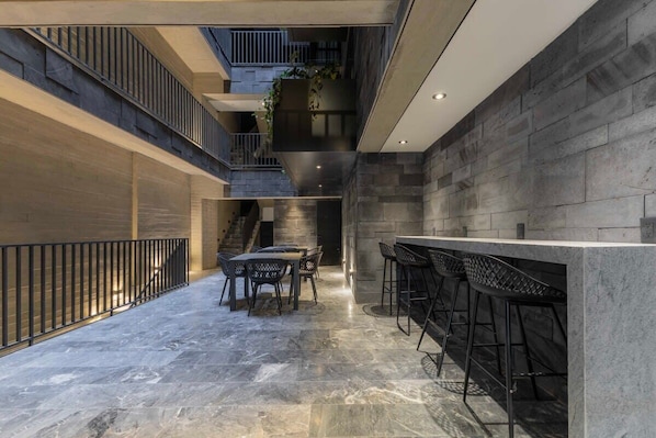 A modern interior with a bar area, seating, and a staircase.