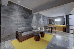 A modern living room with a gray stone wall, a gray sofa, and a yellow rug.