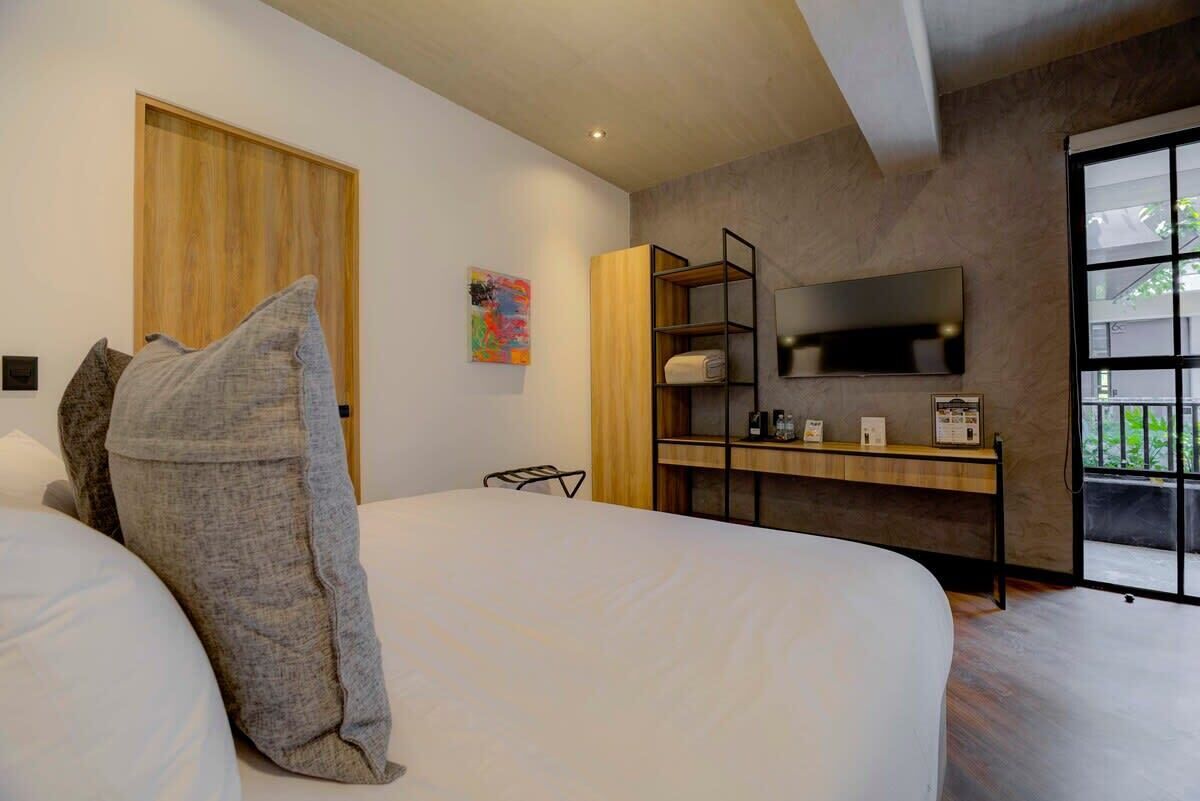 Een moderne slaapkamer met een groot bed, een houten garderobe, een bureau met een televisie en een raam met uitzicht.