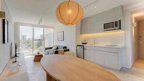 A modern kitchen with a built-in microwave, a large wooden dining table, and a view of the city through large windows. - Capitalia | Breezy A/C & Blazing-Fast Wi-Fi (Ciudad de México)