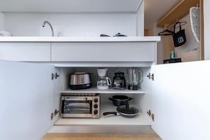 A compact kitchen with a built-in toaster, coffee maker, and a pot on the countertop.