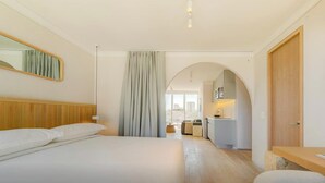 A hotel room with a large bed, a wooden headboard, a mirror, a wardrobe, and a view of the city through a window. - Capitalia | Breezy A/C & Blazing-Fast Wi-Fi (Ciudad de México)